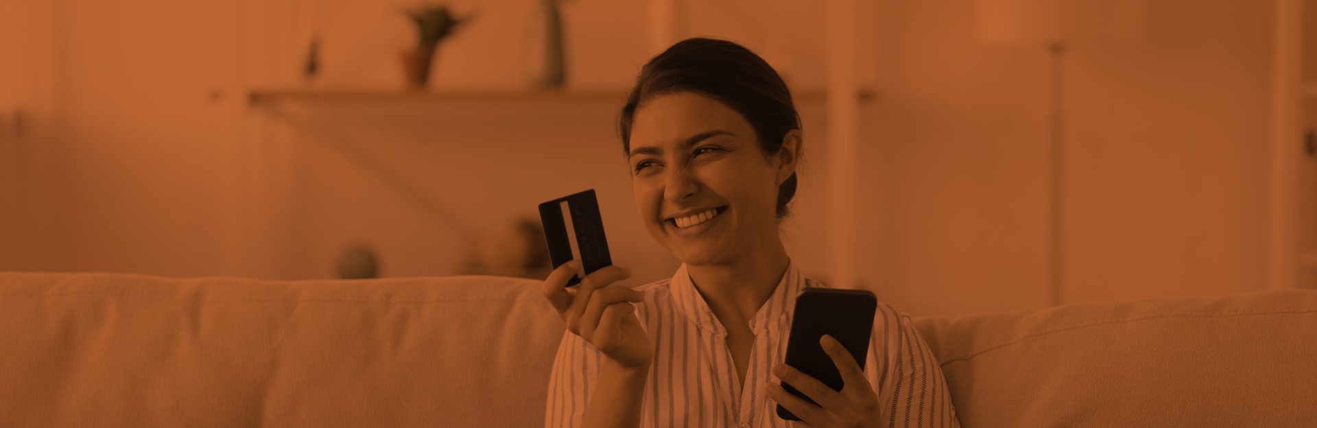 woman smiling and holding credit card and cell phone in hands